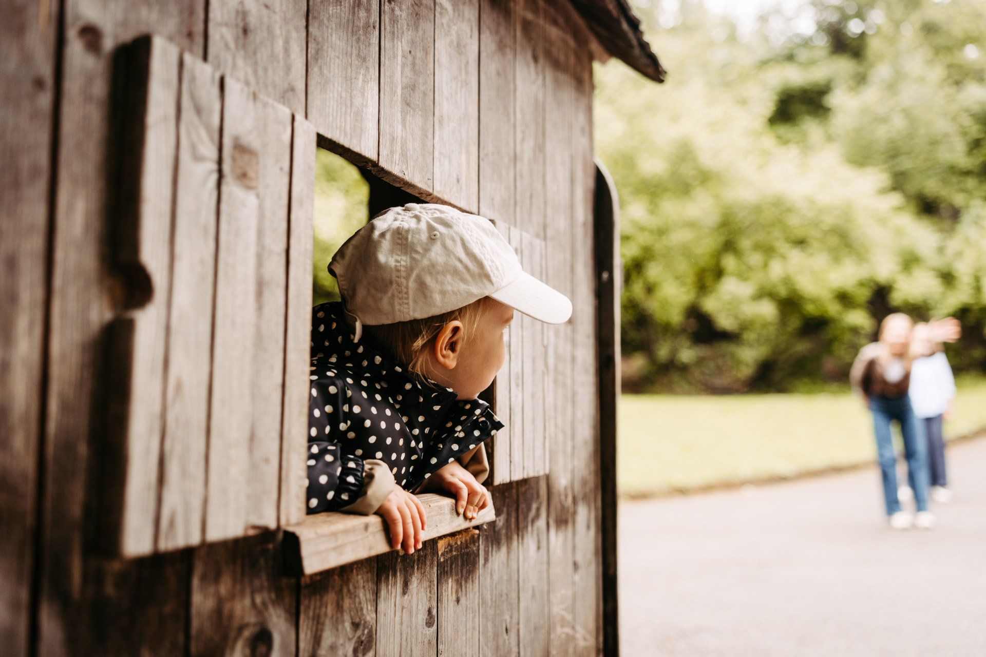 Kind blickt aus einem Holzspielhaus ins Freie